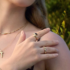 Goldenes Zirkonia-Ring-Set und mehrlagige Halskette getragen von einem Model im Freien