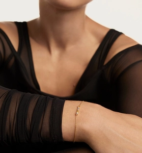 Close-up of a delicate gold chain bracelet with colorful micro zircons on a wrist