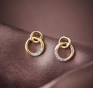 Macro shot of gold double-hoop earrings with sparkling pavé diamonds on silk