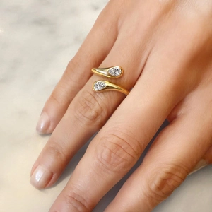 S925 silver golden bypass ring with double pear-shaped cubic zirconia on marble background