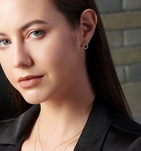 Close-up of elegant double-loop gold earrings with diamonds worn by a model
