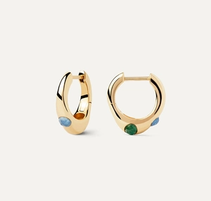 Detail of gold chunky hoop earrings with blue and green gemstones on beige background
