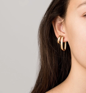 Close-up of elegant gold hoop earrings set on model ear for a layered jewelry look