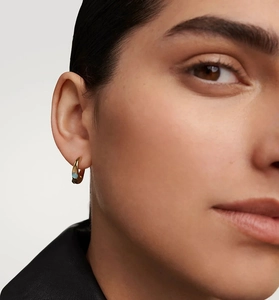 Detail of S925 silver gold hoop earring with an irregular light blue zircon on model ear