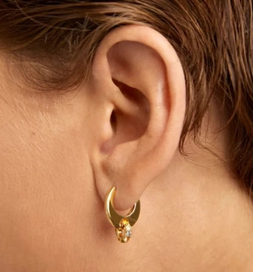 Detail of model wearing gold crescent earrings with micro-pave white crystals on lower ring