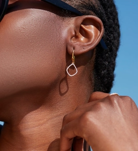 Close-up of gold geometric hollow earrings and matching ring with sparkling pavé crystals