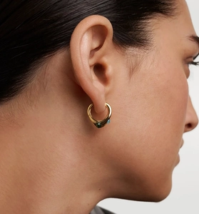 Detail of a gold hoop earring with blue and green zircons worn by a model