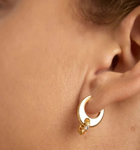 Macro detail of gold crescent moon earring with multicolored cubic zirconia gemstones