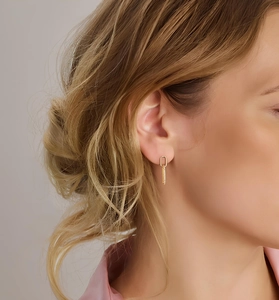 Detailed view of elegant gold geometric earring pendant on a model with minimalist style