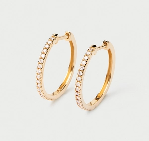 Macro detail of gold hoop earrings with sparkling zircon inlay and polished finish