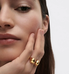 Close-up of a model wearing a gold asymmetric double-sphere open ring in a modern style