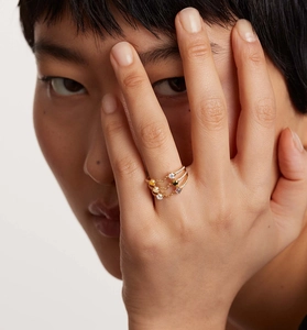 Close-up of stacked gold rings with colorful gemstones on a model hand with soft lighting