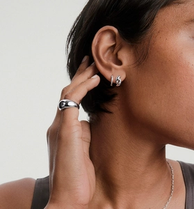 Détails macro des boucles d'oreilles torsadées en argent S925 et bague sur modèle