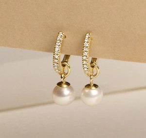 Macro shot of gold hoop earrings with pavé crystals and round white pearl pendants