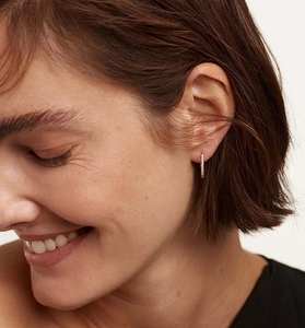 Close-up of minimalist gold hoop earring with pave cubic zirconia on a model's ear