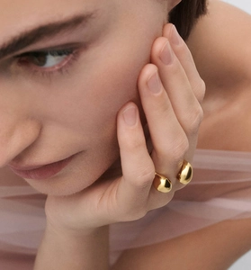 Artistic close-up of a minimalist gold asymmetrical waterdrop ring worn by a model