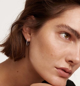 Detailed view of pavé-set silver hoop earrings worn on ear with sparkling zircon stones