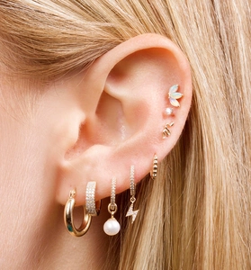 Macro detail of gold earrings set with pearls, diamonds and opal on a model's ear