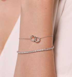 Dettaglio di un bracciale a doppio anello in argento abbinato a un bracciale tennis