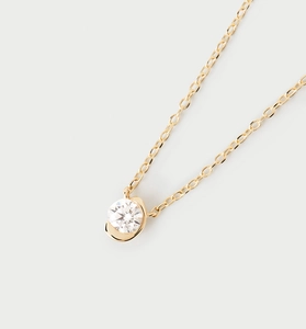 Vue macro d'un collier doré avec un zircon rond brillant monté dans un serti demi-lune