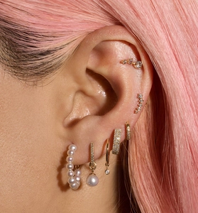 Detailed view of layered 18K gold plated earrings with pearls and cubic zirconia on model