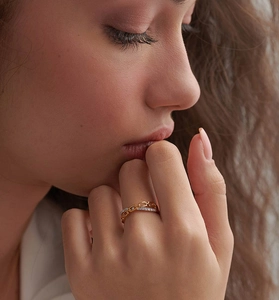 Macro shot of gold chain link ring with pavé diamond accents worn on finger