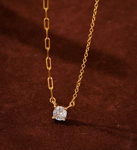 Close-up of gold chain necklace with asymmetric links and a round zircon pendant
