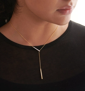 Close-up of minimalist gold Y-shaped lariat necklace with crystal bar on female model