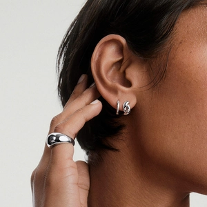 Boucles d'oreilles torsadées en argent 925 et bague large portées par un mannequin