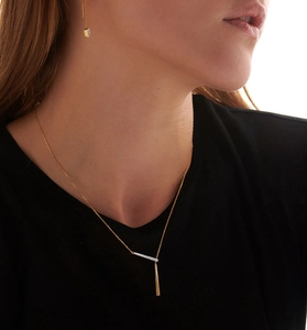 Detailed view of gold geometric pendant necklace with micro-pave crystals on black clothing