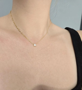 Detail showing gold asymmetrical paperclip chain necklace with a round claw-set crystal