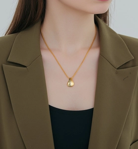 Close-up of a gold water-drop pendant necklace with brushed texture on a female model