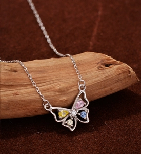 Gros plan d'un pendentif papillon en argent avec zircons colorés sur socle en bois