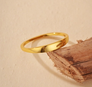 Detailed view of a minimalist gold band ring polished on a natural wood surface