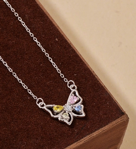 Détail du collier papillon en argent avec pierres colorées sur boîte d'exposition