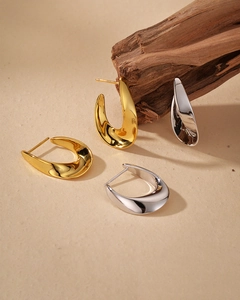 Macro shot of minimalist twisted chunky hoop earrings in gold and silver mirror finish