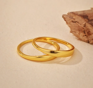 Detailed view of irregular minimalist gold rings on a natural textured background