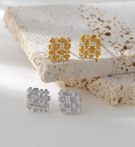Macro shot of geometric lattice brushed earrings with diamonds in gold and silver finish
