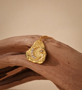 Close-up of golden irregular textured moon and star pendant necklace on rustic wood