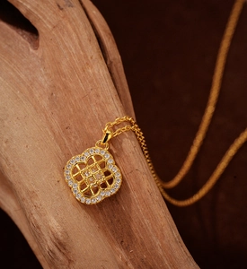 Gros plan d'un pendentif trèfle doré avec motif ajouré et pavé de zircons brillants
