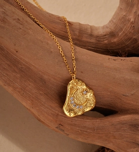 Macro view of gold crescent moon pendant with micro-pave zircons and lava texture