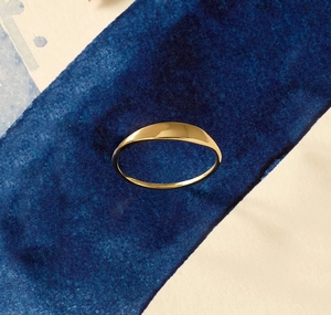 Close-up of polished 14K gold minimalist ring with smooth signet top and inner engraving