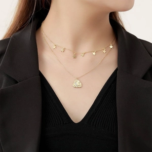 Detail of layered gold moon star necklace on model with irregular texture pendant