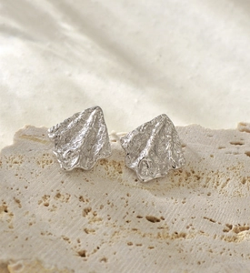 Vue macro de boucles d'oreilles en argent 925 à texture lave sur un support en pierre
