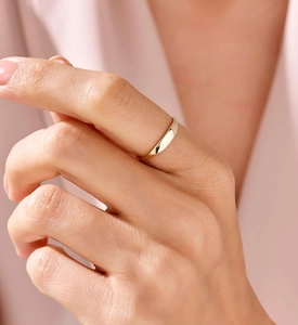 Close-up of minimalist gold ring on index finger with smooth polished finish