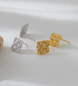 Close-up of square lattice-textured earrings in 18K gold and silver plating with tiny stones