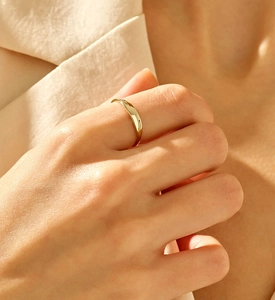Minimalist gold band ring on finger with polished metallic finish and elegant shine