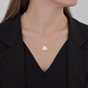 Elegant gold necklace with irregular textured moon pendant worn on black suit outfit