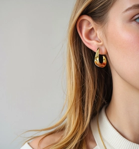Close-up of elegant gold twisted curved hoop earrings worn by a model in daily style