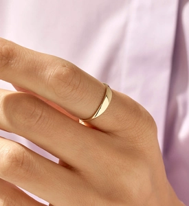 Close-up of a high-polished gold minimalist ring worn on finger with soft lighting